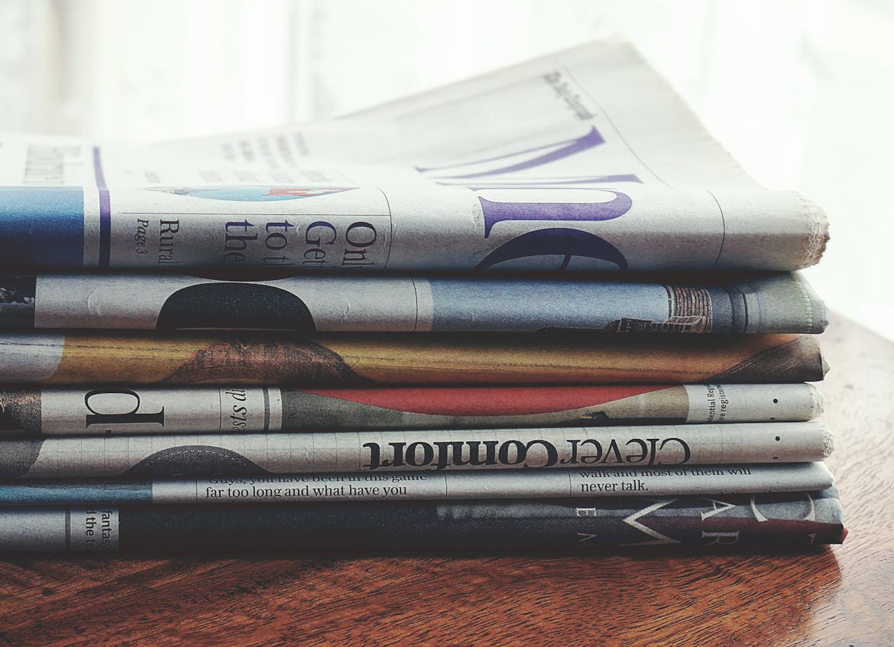 A stack of folded newspapers placed on a wooden table, symbolizing news and information.